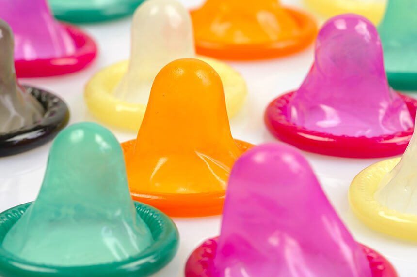 varios preservativos coloridos sobre uma superficie branca