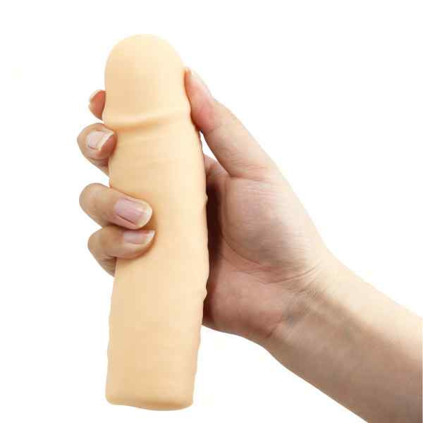 mão feminina segurando capa peniana cyberskin extensora na cor bege