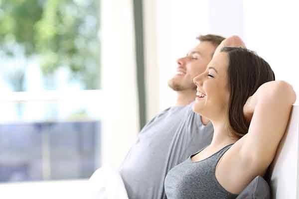 casal de homem e mulher brancos sentados na cama relaxando e respirando fundo em referência controle do orgasmo e edging