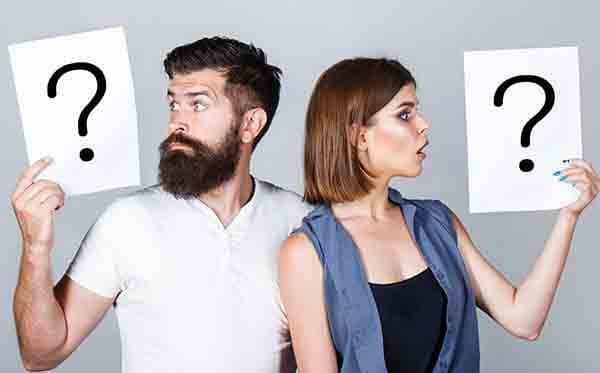 casal cada um segurando um cartaz com interrogação