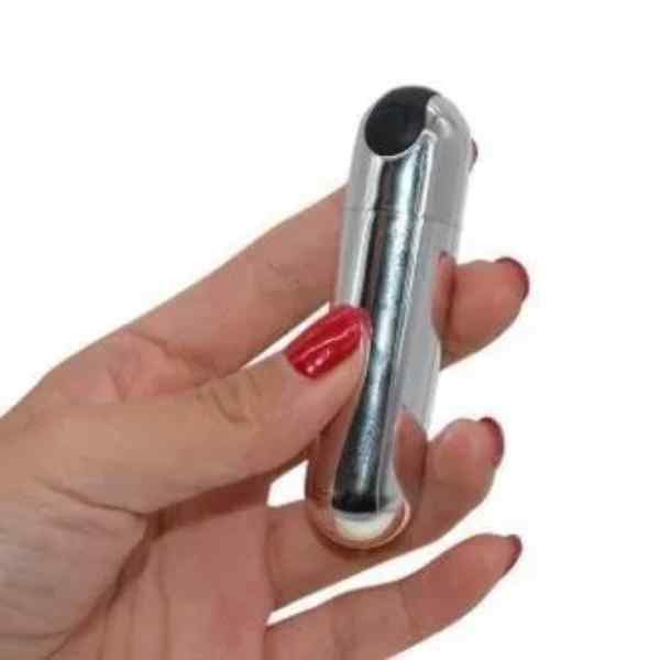mão feminina segurando capsula bullet vibratório prateado