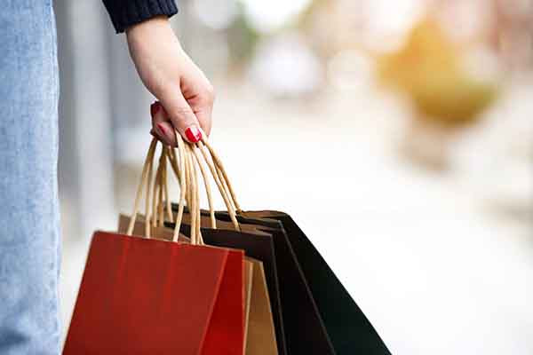 mão feminina segurando sacolas coloridas de compras em shopping