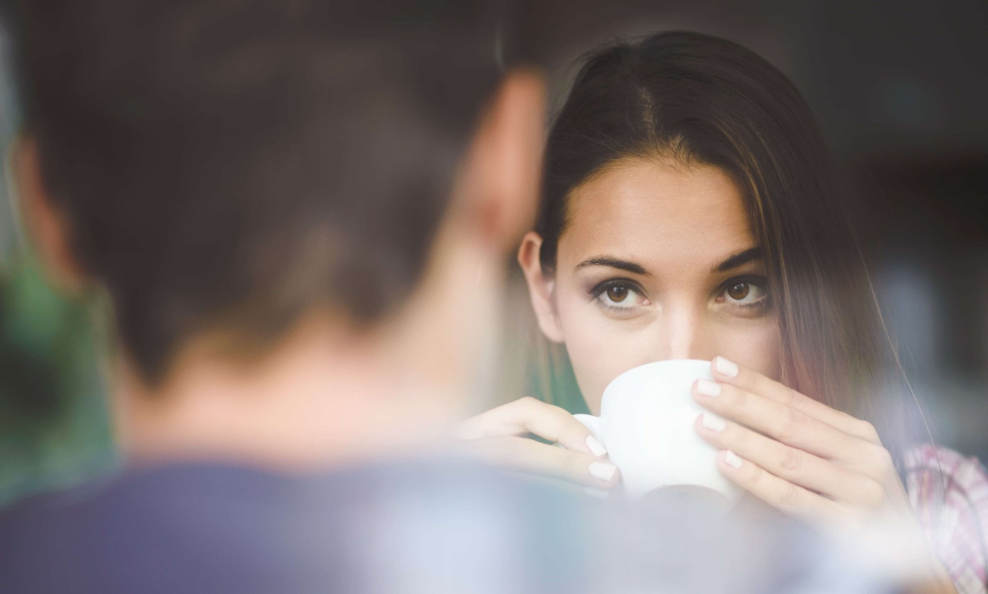 Golpes do Tinder, uma mulher bebendo algo na caneca, olhando para a frente, olhando de frente para um homem , o homem está de costas para câmera e a imagem só mostra a sua cabeça e nuca