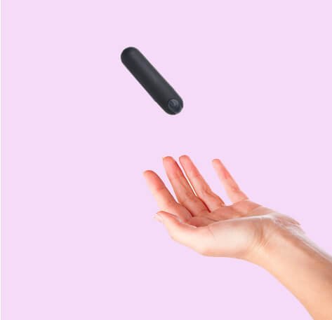 foto montagem de mão feminina aberta para apanhar vibrador bullet preto fundo rosa